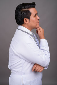 Side view of young man looking away against black background