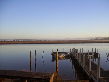 Wooden pier in lake against clear sky