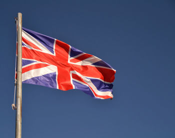Low angle view of british flag against clear blue sky