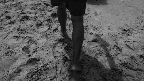 Low section of a man walking on sand