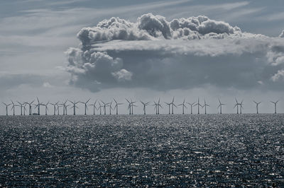 Solar windmills in the sea against a cloudy sky.