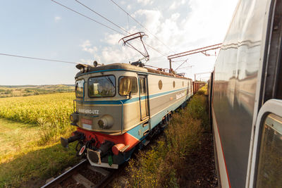 Train on railroad track amidst field against sky