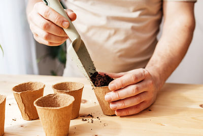 A man is sowing seeds in ecological peat cups. a man is shoveling soil for planting. gardening 