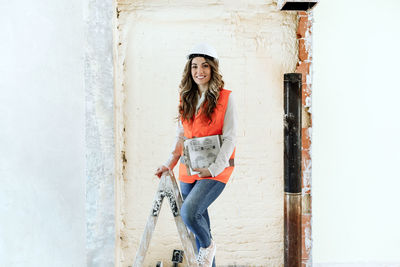 Professional confident architect woman in construction site standing on ladder. home renovation