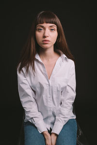 Portrait of beautiful young woman over black background