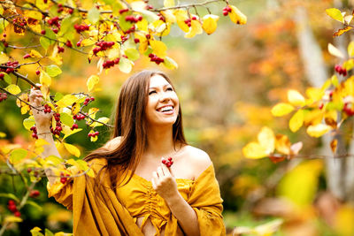 Young woman looking up while standing by fruit trees