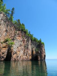 Rock formations by sea against clear sky