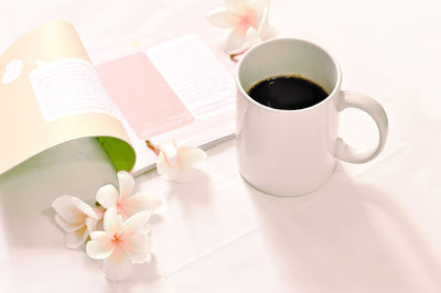 Coffee cup and white roses on table