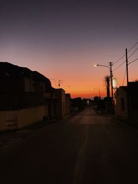 Street amidst buildings against sky during sunset