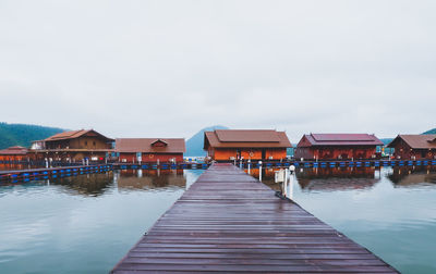 Pier amidst swimming pool by lake against sky