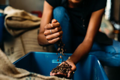 Midsection of woman with roasted coffee beans in crate