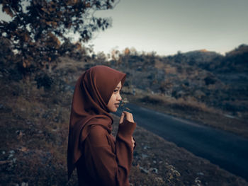 Side view of woman standing on land against sky