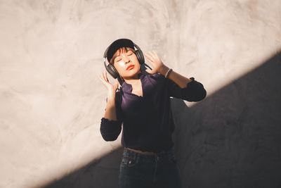 Full length of young woman standing against wall