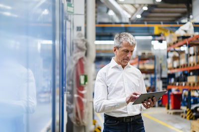 Mature businessman using tablet pc in factory