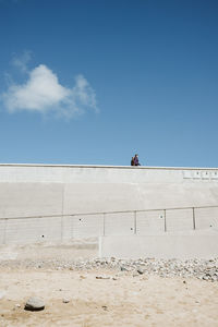 Low angle view of man sitting against wall