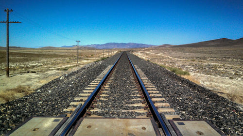 Railroad tracks against clear blue sky