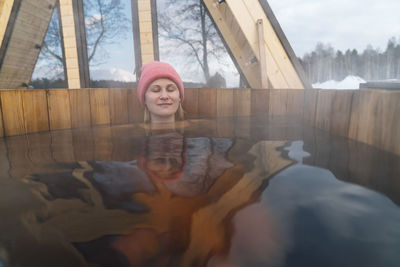 Woman with eyes closed relaxing in hot tub outside house