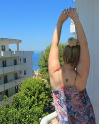 Rear view of woman stretching in balcony