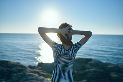 Woman standing by sea against clear sky