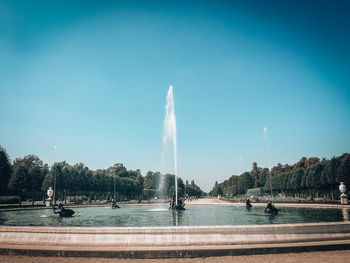 Fountain by lake against clear sky