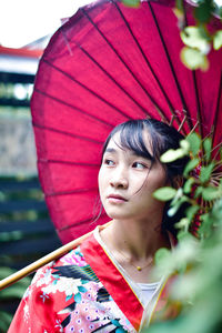 Close-up of young woman with umbrella looking away