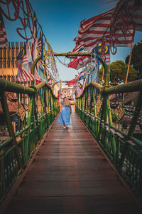 Rear view of woman walking on footbridge