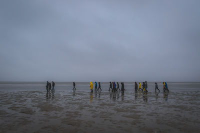 People at beach against sky