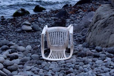 Abandoned chair on pebbles at beach