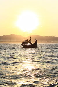 Silhouette boat in sea against sky during sunset