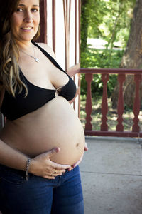 Seven months pregnant young woman dressed in black bikini and jeans