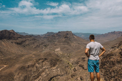 Rear view of man on mountain against sky