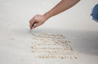 Close-up of woman drawing at beach with stick 