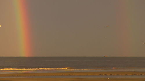 Scenic view of rainbow over sea against sky