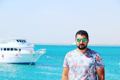 Portrait of young man standing in sea against clear sky