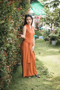 Portrait of young woman standing by plants