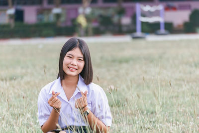 Portrait of young woman sitting on field