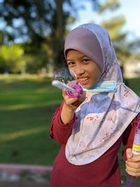 Girl holding a smiling while standing against blurred background