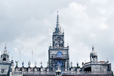 Low angle view of clock tower against cloudy sky