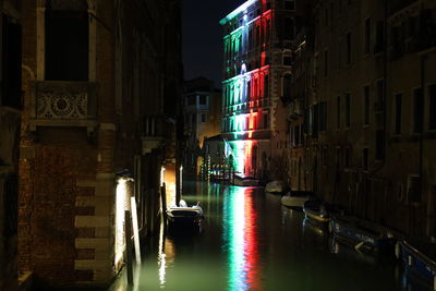 Canal amidst buildings in city at night