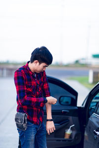 Full length of young man standing in car