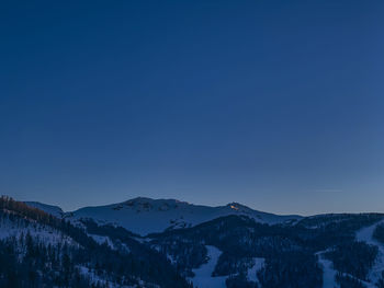 Scenic view of snowcapped mountains against clear blue sky