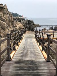 Walkway by sea against sky