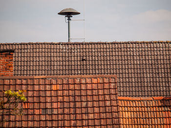 Lamp post on roof against sky