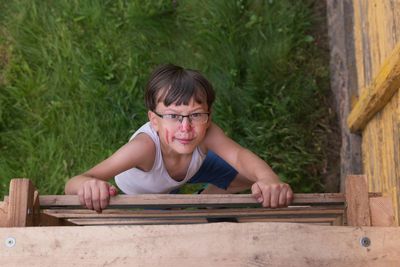 Portrait of boy sitting on wooden fence