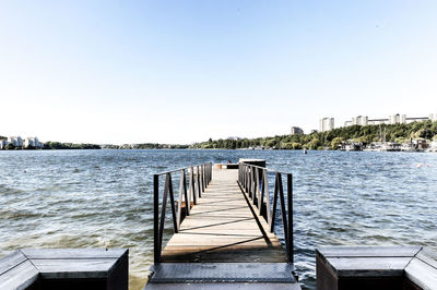 Pier over sea against clear blue sky