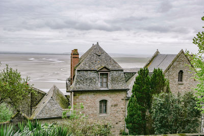 Houses and trees by building against sky