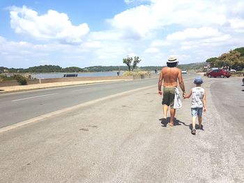 Rear view of people walking on road against sky