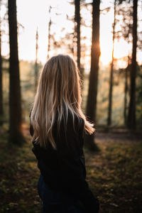 Rear view of woman standing on field in forest