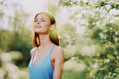 Young woman standing against plants