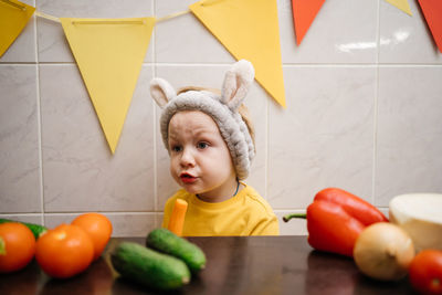 Baby in rabbit ears eats vegetables carrot cucumber easter